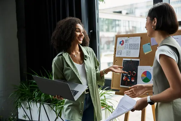 A lesbian couple work in an office, discussing charts. — Stock Photo