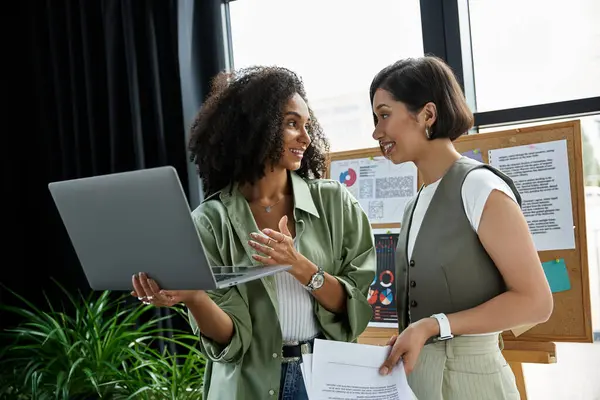 Dos mujeres están en una oficina, discutiendo el trabajo mientras miran un portátil. — Stock Photo