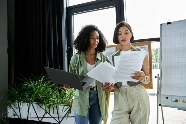 Two women working together in an office, reviewing documents. — Stock Photo