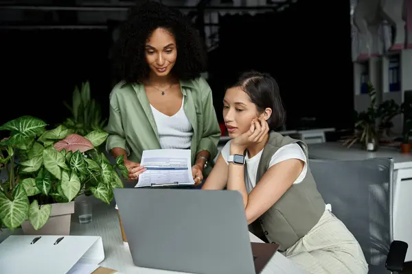 Two women review documents at a modern office desk. — Stock Photo