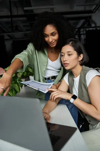 Two women work together on a laptop in an office setting. — Stock Photo