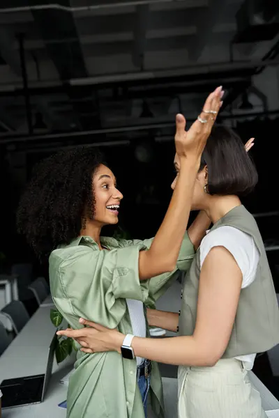 Deux femmes dans un bureau célèbrent un succès ensemble, les bras levés dans la joie. — Photo de stock