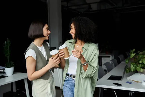 A lesbian couple share a coffee break, laughing and talking. — Stock Photo