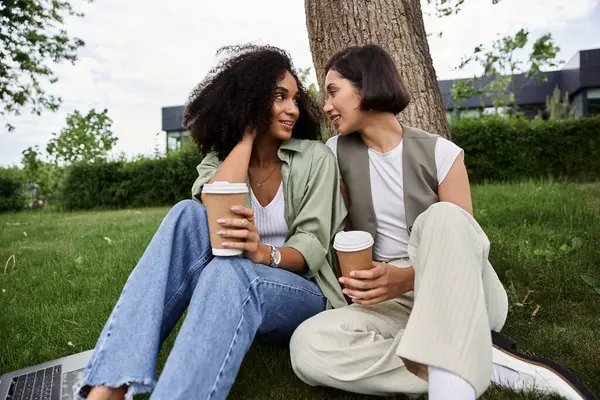 Duas mulheres compartilham um momento amoroso durante uma pausa para o café fora. — Fotografia de Stock