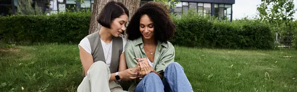 Two women, dressed casually, sit together in a park and look at each other with affection. — Stock Photo