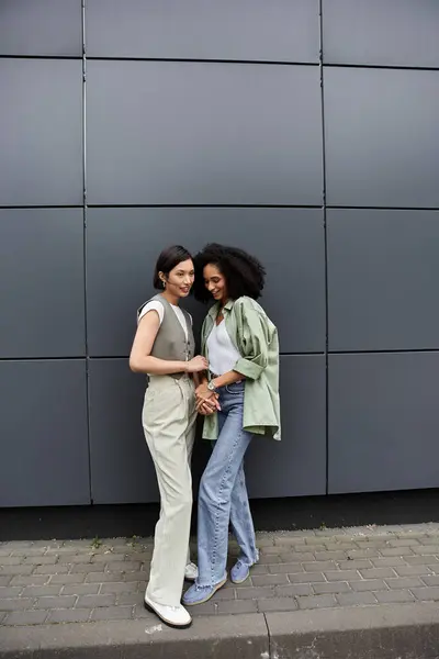 Лесбійська пара посміхається і тримає руки, стоячи на вулиці міста. — стокове фото