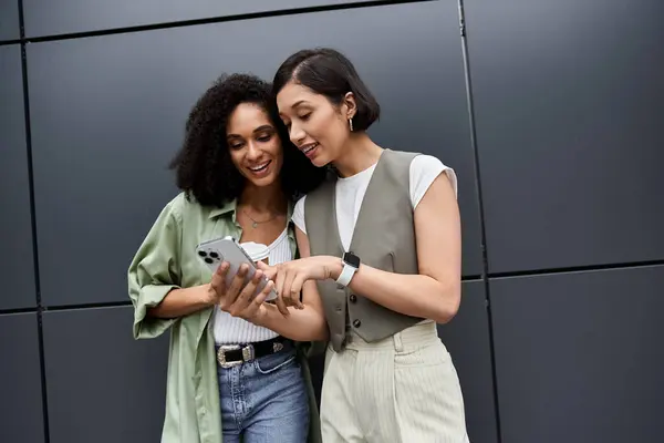 Дві жінки в офісі, посміхаючись і дивлячись на смартфон разом. — Stock Photo