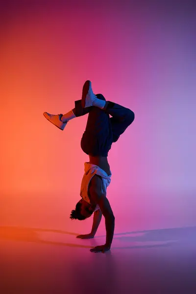 A young African American man performs a handstand against a colorful, gradient background. — Stock Photo