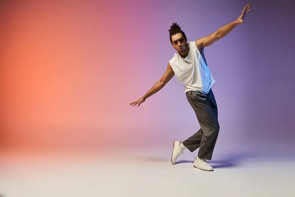 A young African American man dances with style against a vibrant gradient backdrop. — Stock Photo