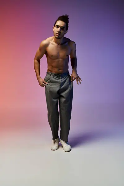 A young African American man dances on a background of pink and purple hues, showcasing his skills and confident expression. — Stock Photo