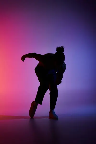 Silhouetted African American man dances energetically against vibrant background, showcasing contemporary movement. — Stock Photo