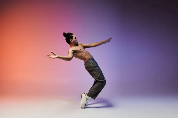 A young African American man dances on a colorful gradient background, showcasing his athleticism and grace. — Stock Photo