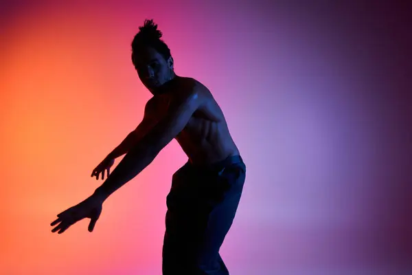 A young African American man dances in silhouette against a colorful gradient background. — Stock Photo