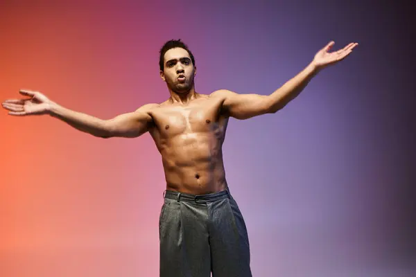 A young African American man dances with his arms outstretched against a colorful gradient background. — Stock Photo