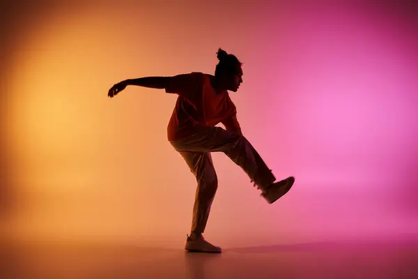 A young African American man dances in silhouette against a vibrant orange and pink gradient background. — Stock Photo