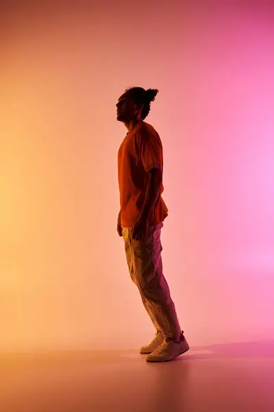 A young African American man dances in a studio, lit by vibrant gradient lighting. — Stock Photo
