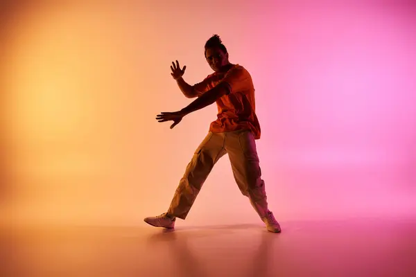 Un jeune Afro-Américain danse dans un studio avec un fond dégradé coloré. — Photo de stock