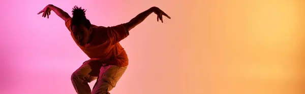 A young African American man dances in silhouette against a vibrant gradient background. — Stock Photo