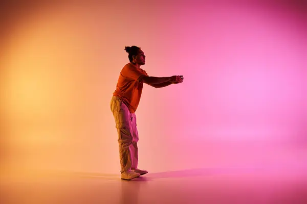 Молодий афроамериканський чоловік танцює з грацією та енергією на яскравому градієнтному фоні. — стокове фото