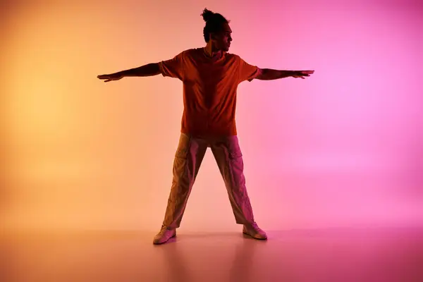 Un joven afroamericano baila en un escenario iluminado por luces de neón rosas y amarillas. - foto de stock