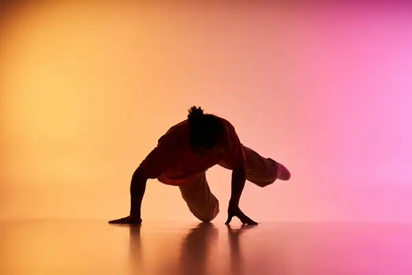 A young African American man dances on a vibrant gradient background. — Stock Photo