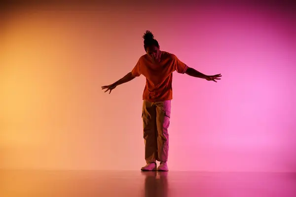 An African American young man dances and poses against a colorful gradient background, lit by studio lighting. — Stock Photo