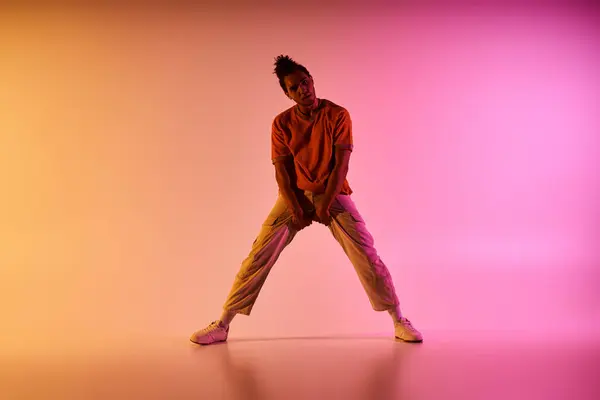 Un jeune danseur afro-américain pose devant un fond dégradé de jaune, d'orange et de rose. — Photo de stock