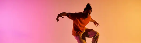 A young African American man dances with vibrant energy against a colorful gradient background. — Stock Photo