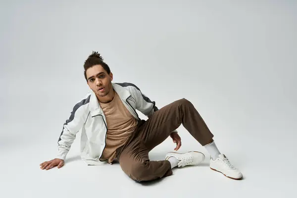 A young African American man in a stylish outfit poses against a grey background. — Stock Photo