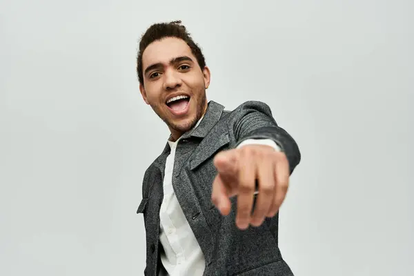 A stylish African American man in a coat, smiles and points at the camera in a studio setting. — Stock Photo