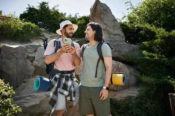 Um jovem casal gay caminha através de uma paisagem de verão, compartilhando uma risada e desfrutando de seu tempo juntos. — Fotografia de Stock