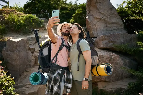 A gay couple takes a selfie while hiking in the wilderness on a sunny summer day. — стоковое фото