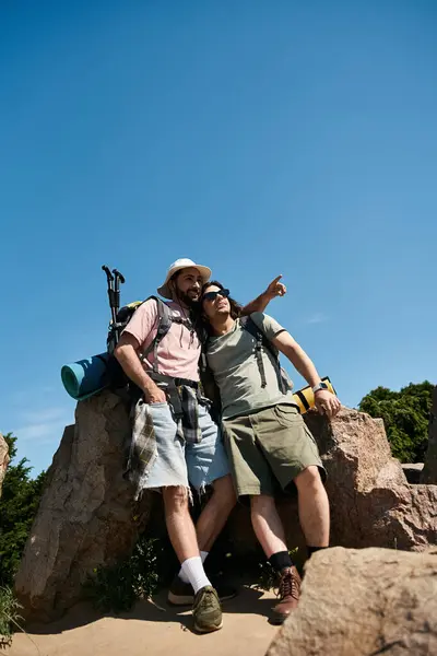 Um casal gay caminha juntos através da natureza em um dia ensolarado de verão, apreciando a vista de uma vista rochosa. — Fotografia de Stock