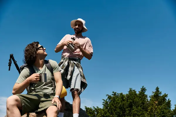 Two young men, a gay couple, are hiking in the wilderness on a sunny day. They are enjoying the outdoors and each others company. — Stock Photo