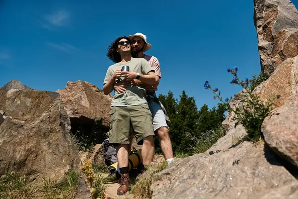 A gay couple enjoys a summer hike, embracing amongst the rocks and trees, creating a loving moment in nature. — стоковое фото