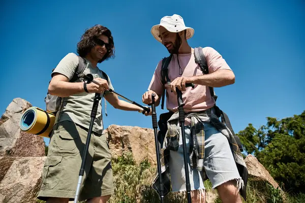 Dois jovens, um casal gay, caminham juntos através de uma paisagem rochosa em um dia ensolarado de verão. — Fotografia de Stock