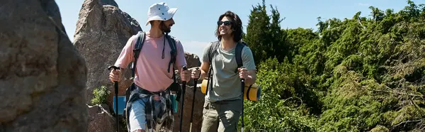 A young gay couple hikes through a lush, green forest on a sunny summer day. — Stock Photo