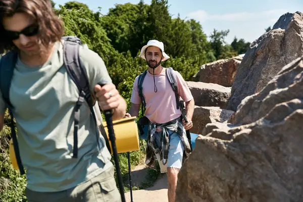 Dois jovens, um casal gay, caminham juntos em um cenário natural deslumbrante, apreciando a beleza do verão ao ar livre. — Fotografia de Stock