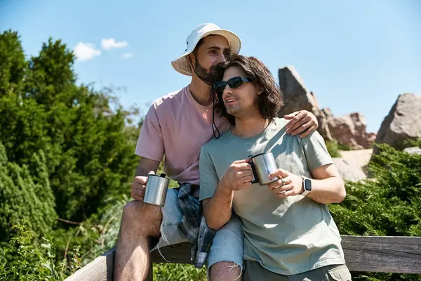 A young gay couple enjoys a summer hike together, stopping to take in the view and share a moment of love. — Stock Photo