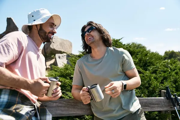 Two young men, a gay couple, hike in nature together on a sunny summer day. They are smiling and laughing as they enjoy the outdoors. — Stock Photo
