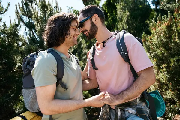 Um jovem casal gay desfruta de um dia ensolarado na natureza, caminhando por uma floresta exuberante, compartilhando momentos de intimidade enquanto dá as mãos. — Fotografia de Stock