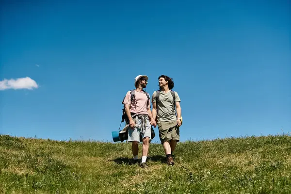 Two young men hike together in a beautiful, grassy landscape on a sunny day. — Stock Photo