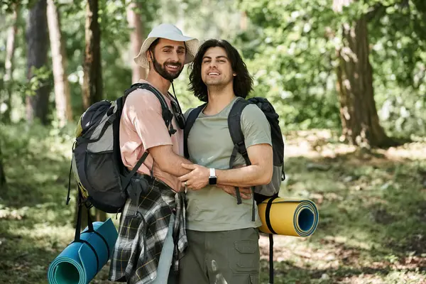 Un jeune couple gay sourit pour la caméra lors d'une randonnée dans le désert par une journée d'été ensoleillée. — Photo de stock