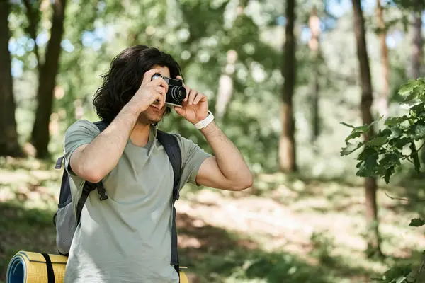 A young man hikes through the woods on a sunny summer day, capturing the beauty of nature with his camera. — Stock Photo
