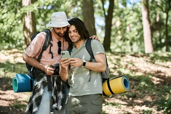 Dois jovens caminham por uma floresta, verificando seu telefone e aproveitando o clima de verão. — Fotografia de Stock