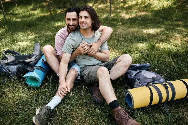 Una joven pareja gay disfruta de una caminata de verano en el desierto, abrazando y sonriendo con amor mientras se toman un descanso. - foto de stock