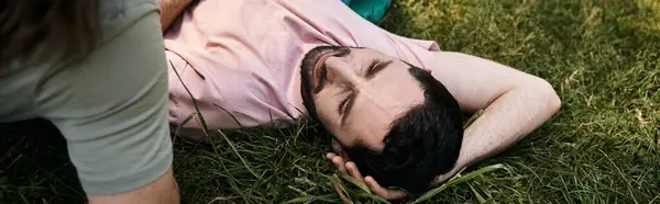 A young gay couple enjoying a summer hike together, lying down in the grass to soak up the sun. — Stock Photo