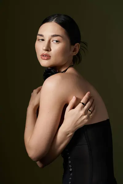 A young woman with brunette hair and a flower choker necklace poses against a black background. — Stock Photo
