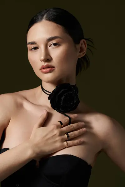 A young woman poses against a black backdrop, wearing a black velvet choker adorned with a large rose and multiple rings. — Stock Photo