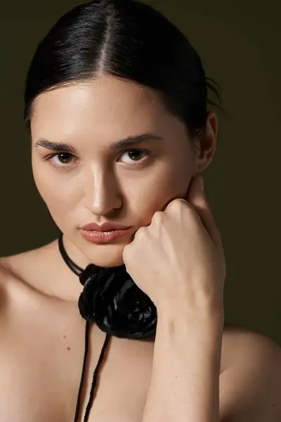 A young woman with brunette hair poses with a flower choker on a black background. — Stock Photo